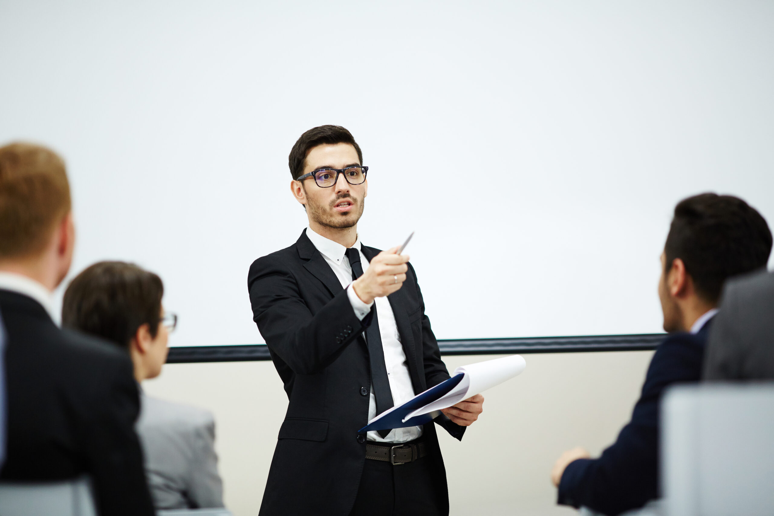 Confident coach pointing at one of listeners while making report at training